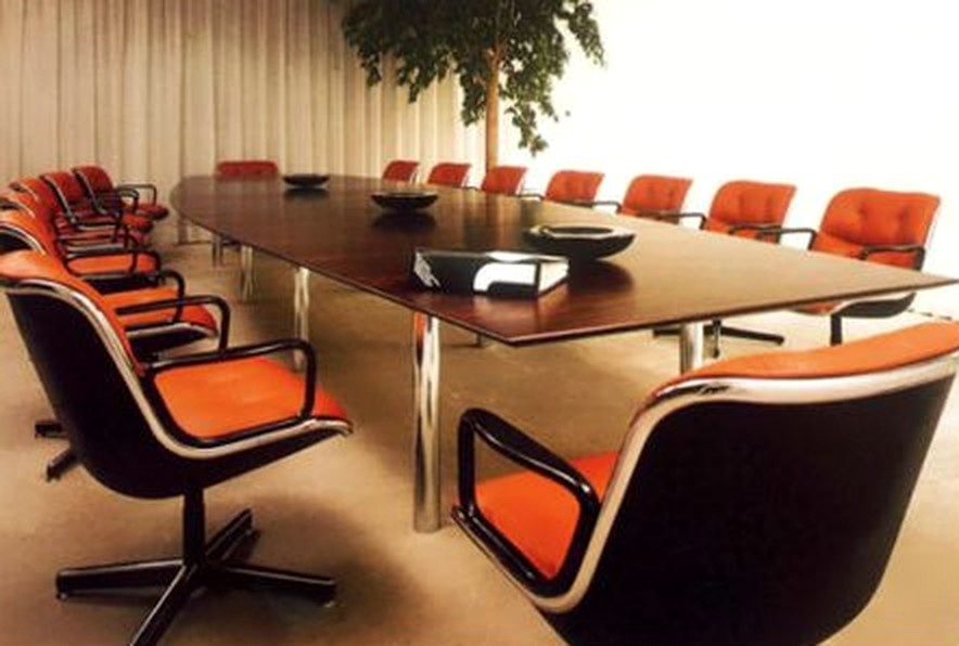 a long wood conference table lined with orange pollock executive chairs