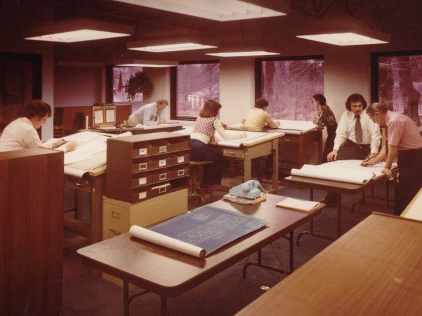 architects and drafters at drawing tables in a 1970s office