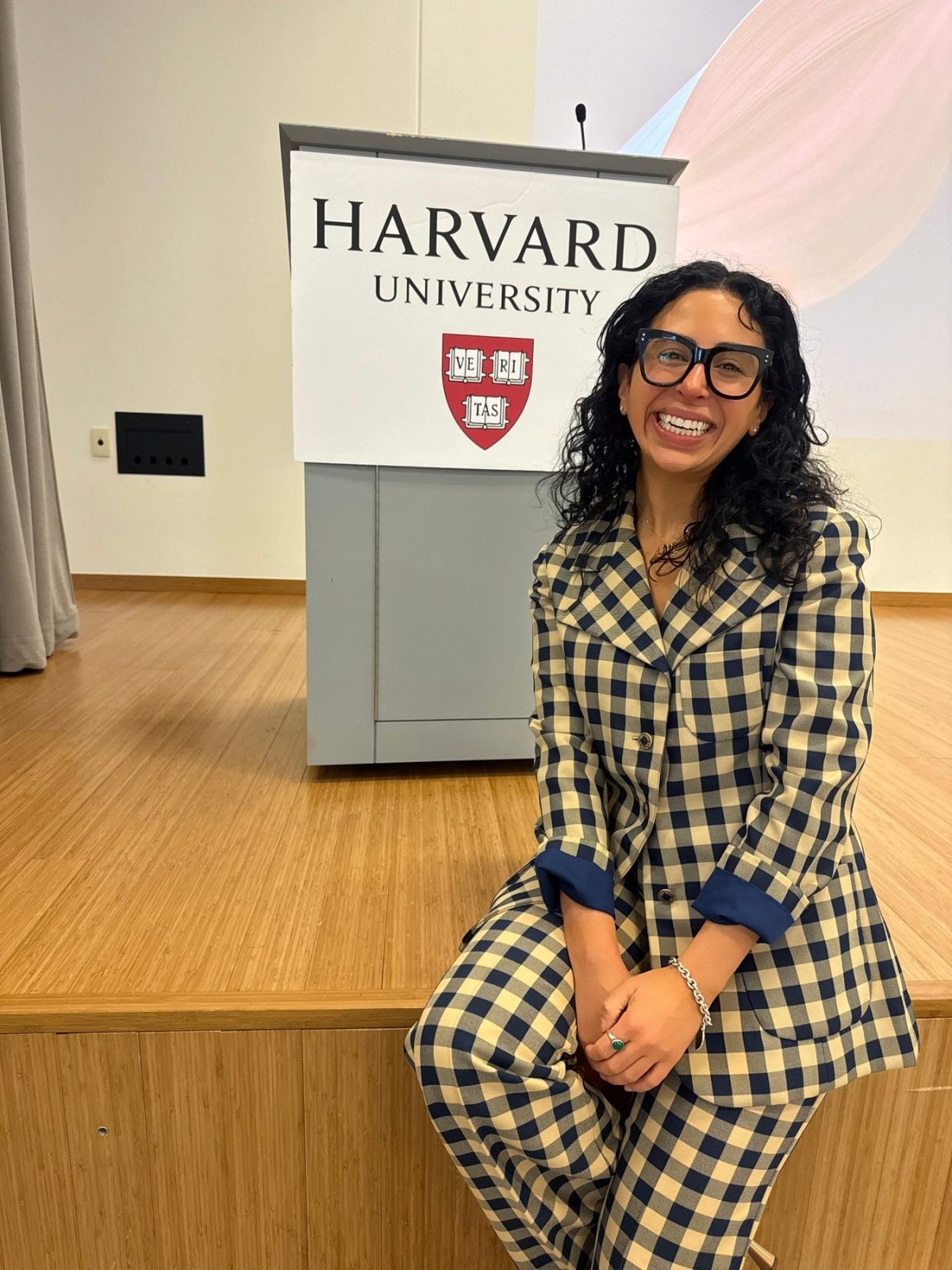 hailey seated on stage beside a harvard university podium