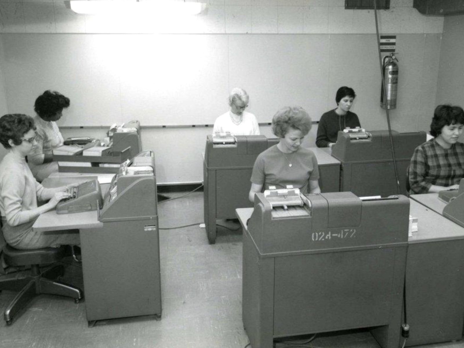 women working at keypunch machines in a data processing room, black and white