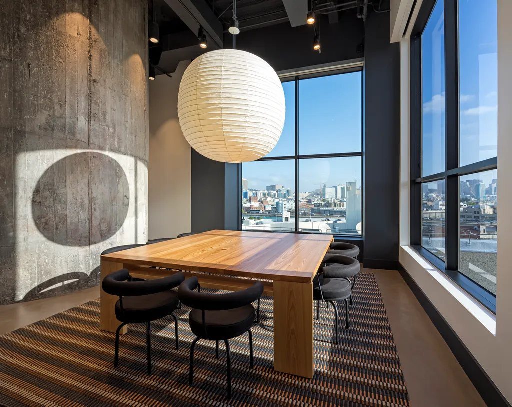a quiet conference room with a wooden table, a paper lantern, and city views