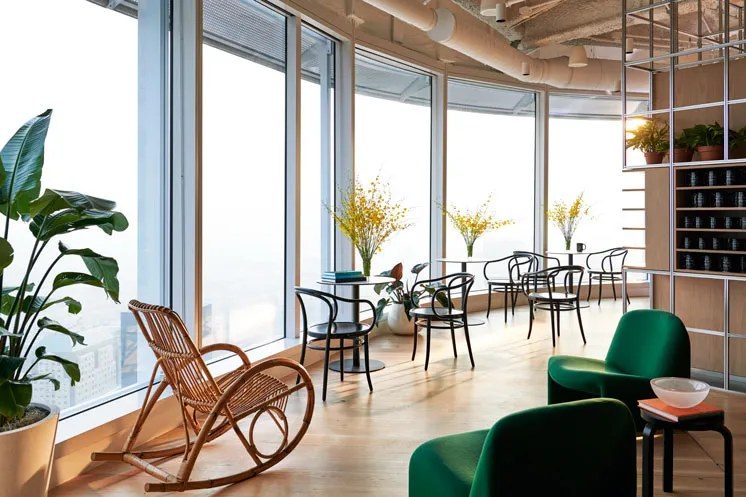 a bright office lounge with green chairs and city views