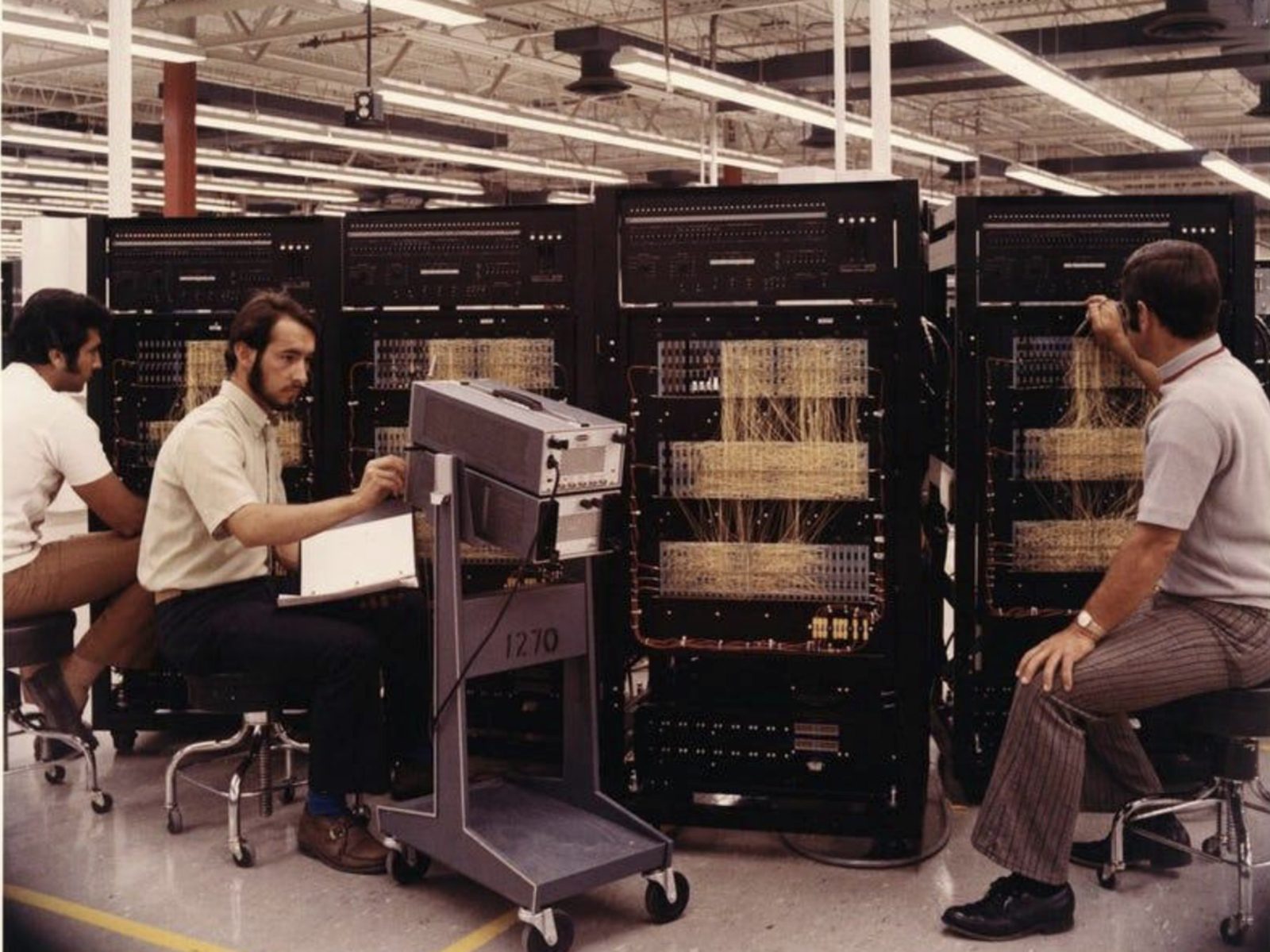 three technicians wiring the back of computer cabinets by hand